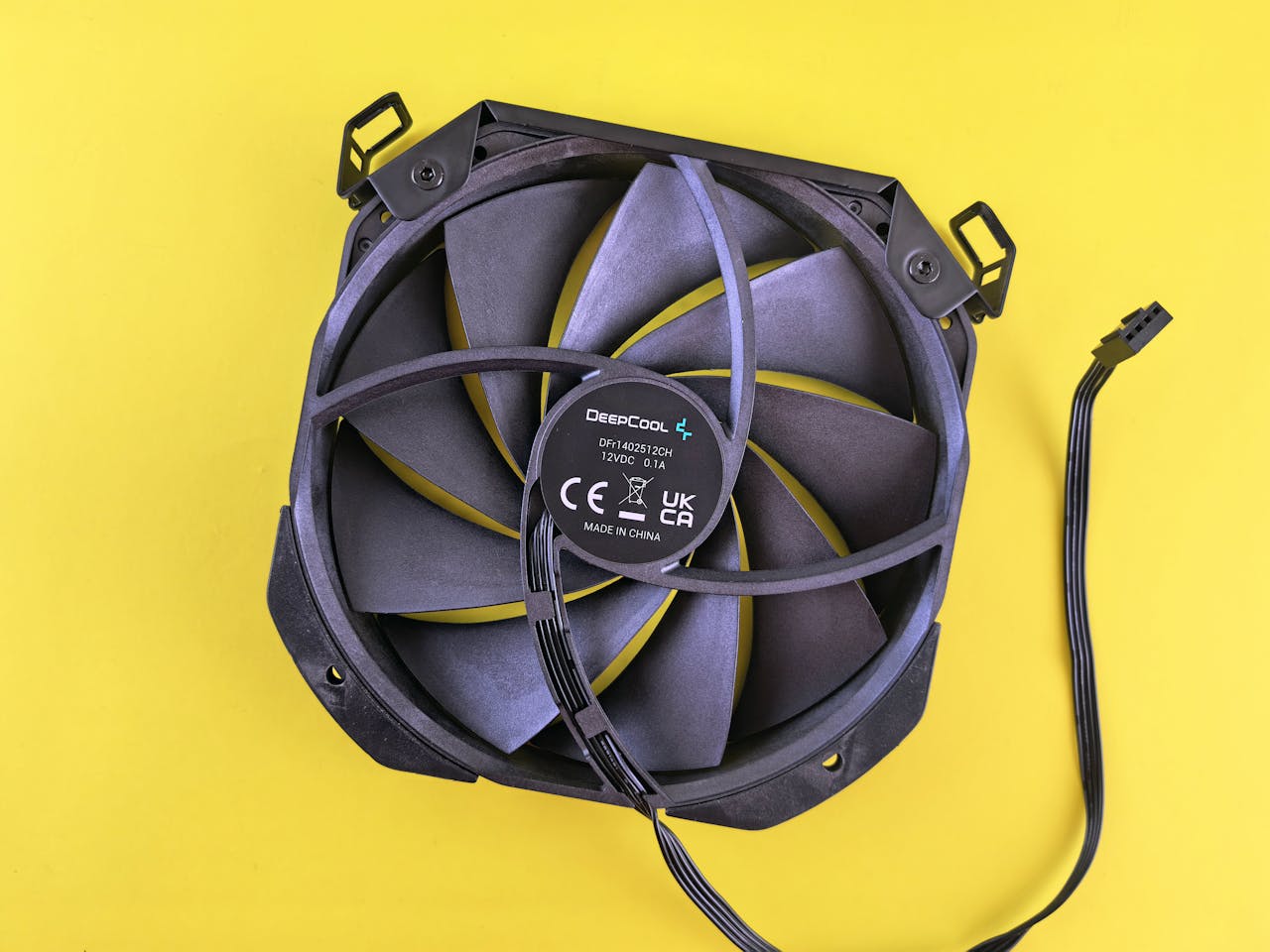 Black computer cooling fan with wire on vibrant yellow background. Ideal for technology content.